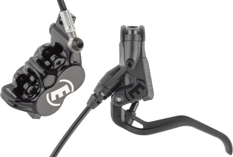Close-up of Magura MT Thirty hydraulic disc brake mounted on an e-bike fork showing its 4-piston caliper in action